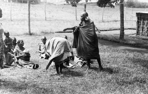 Government de-oathing ceremony. Female Mau Mau detainees undergo a government de-oathing ceremony in a fenced compound, performed to 'purify' them of the Mau Mau oath. Kenya, circa 1954. Kenya, Eastern Africa, Africa.