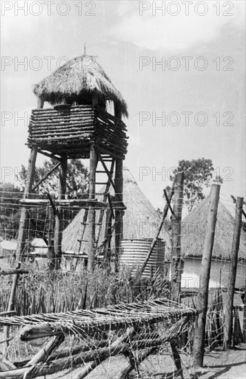 Kikuyu Home Guard watchtower. A wooden watchtower or observation tower rises above the heavily fortified compound of a Home Guard post. Kenya, circa 1953. Kenya, Eastern Africa, Africa.