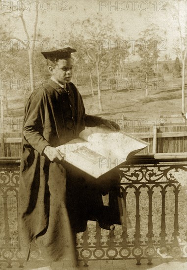 Professor Goosey', Australia. Staged amateur portrait of 'Professor Goosey', Evan Pughe, dressed up as an academic, reading from a book on a veranda of the Brodribb's family house 'Nundora'. Toowoomba, Australia, circa 1908. Toowoomba, Queensland, Australia, Australia, Oceania.