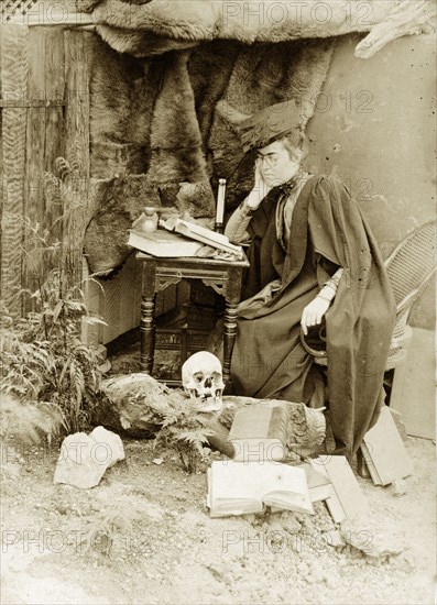 Academic 'hermit', Australia. Staged outdoors portrait of Prunella 'Prue' Brodribb, dressed up as an academic 'hermit' with skull and books. Probably Toowoomba, Australia, circa 1895. Toowoomba, Queensland, Australia, Australia, Oceania.