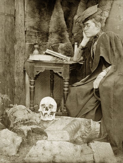 Academic 'recluse', Australia. Staged outdoors portrait of Prunella 'Prue' Brodribb, dressed up as an academic 'recluse' with skull and books. Probably Toowoomba, Australia, circa 1895. Toowoomba, Queensland, Australia, Australia, Oceania.