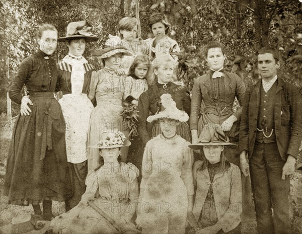 Typical Victorian dress, Australia. Well-dressed and wearing clothes typical of the late Victorian era, a group of young women and children, accompanied by a lone boy, line up for the camera against a backdrop of trees. Queensland, Australia, circa 1895., Queensland, Australia, Australia, Oceania.