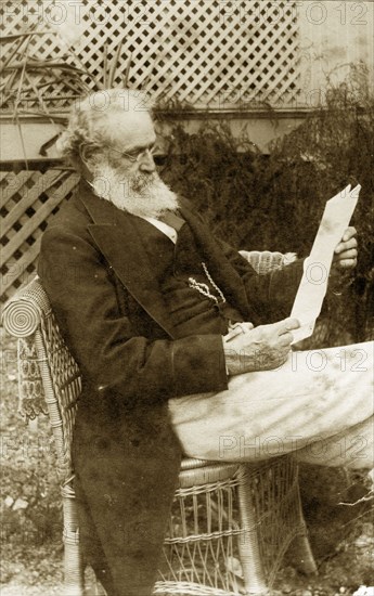 Francis Brodribb relaxes at 'Nundora'. Francis Brodribb (1820-1904) reads thoughtfully from a letter in the garden at the Brodribb family's house 'Nundora'. He wears formal attire: a jacket with long tails teamed with waistcoat and pocket watch. Toowoomba, Australia, circa 1895. Toowoomba, Queensland, Australia, Australia, Oceania.