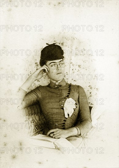 Is this really 'Miss Meadows'?. Although identified as 'Miss Meadows', this woman closely resembles 'Prue' Brodribb. Related images show other members of the Brodribb family dressed as historical or literary characters, and this may be another such example. Wearing what appears to be a deerstalker cap and spectacles, her gloves tucked into the front of her button-up dress. Queensland, Australia, circa 1895., Queensland, Australia, Australia, Oceania.