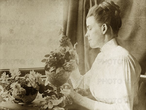 Arranging flowers for a painting. Ellen May Pughe arranges daisy and rose flowers into bowls for a still life composition she will later paint. Near Brisbane, Australia, circa 1895., Queensland, Australia, Australia, Oceania.