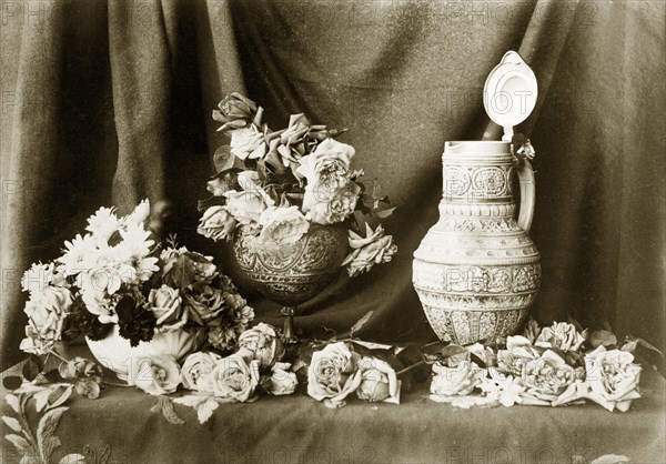 Still life composition, Australia. Roses and daisies spill out around two bowls and an ornate jug, arranged to form a still life composition against a cloth backdrop. Location unknown, circa 1895., Queensland, Australia, Australia, Oceania.