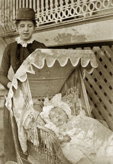 Nurse and baby at 'Nundora'. A Victorian nursemaid pushes a baby in wicker pram decorated with frills outside the Brodribb's family house 'Nundora'. Toowoomba, Australia, circa 1895. Toowoomba, Queensland, Australia, Australia, Oceania.