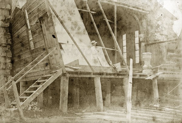 Destruction of a temporary church. A man takes notes inside the ruins of a wooden church constructed on a temporary basis for the community of Indooroopilly. The church's stone font can be seen in the wreckage. Indooroopilly, Australia, circa 1890. Indooroopilly, Queensland, Australia, Australia, Oceania.