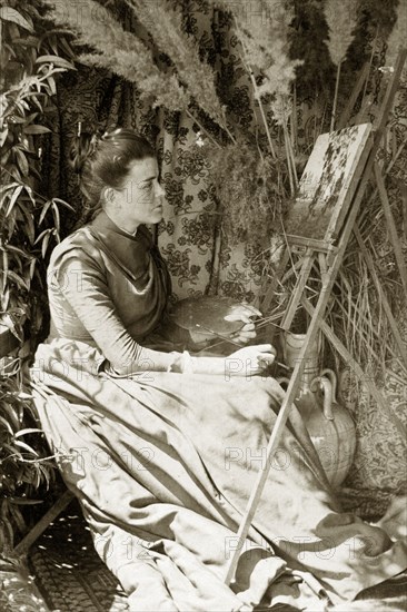 At the easel, Australia. Outdoors portrait of Ellen May Pughe, nee Brodribb, paused thoughtfully in front of a canvas she is completing, palette and paint brush in hand. Near Brisbane, Australia, circa 1895., Queensland, Australia, Australia, Oceania.