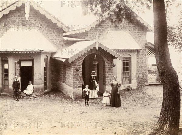 Lieutenant Maslin's bungalow. Supervised by their mother and a finely dressed Indian woman, a family of British children play outside a low building with bay windows and a pitched roof identified as 'Lt. Maslin's Bungalow'. India, circa 1895. India, Southern Asia, Asia.