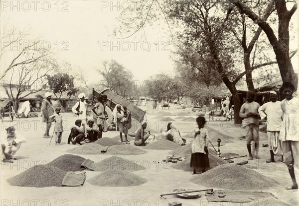 Indian grain market. Street traders at an Indian grain market mill about, their supplies of grain piled neatly into heaps on the ground. India, circa 1895. India, Southern Asia, Asia.