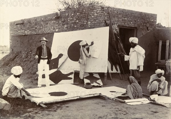 Re-covering targets. A British man instructs a group of Indian workers as they re-cover and re-paint a set of fabric shooting targets. India, circa 1895. India, Southern Asia, Asia.