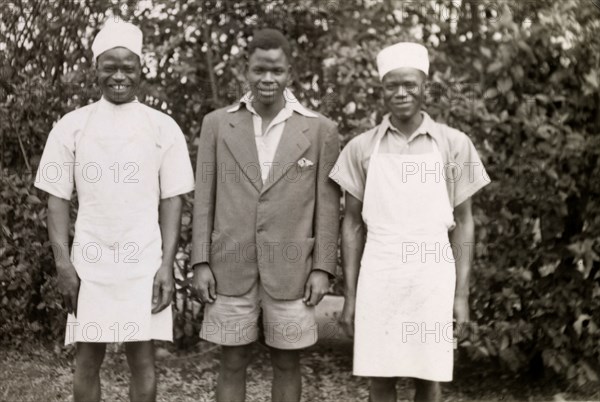 Domestic servants. Three domestic servants in workwear smile for the camera, their roles identified as (left to right): 'Cook, garden and house'. Salisbury, Southern Rhodesia (Harare, Zimbabwe), circa 1949. Harare, Harare City, Zimbabwe, Southern Africa, Africa.