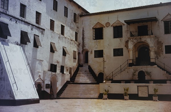 Courtyard of Elmina Castle. The paint-peeled walls of a sunny courtyard inside the walls of Elmina Castle. Ghana, circa 1965. Elmina, Central (Ghana), Ghana, Western Africa, Africa.