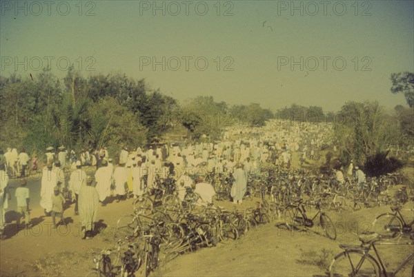 Procession for Ramadan. A procession held to celebrate the end of Ramadan heads into the distance past hundreds of bicycles parked on a roadside verge. Zaria, Nigeria, 1958. Zaria, Kaduna, Nigeria, Western Africa, Africa.