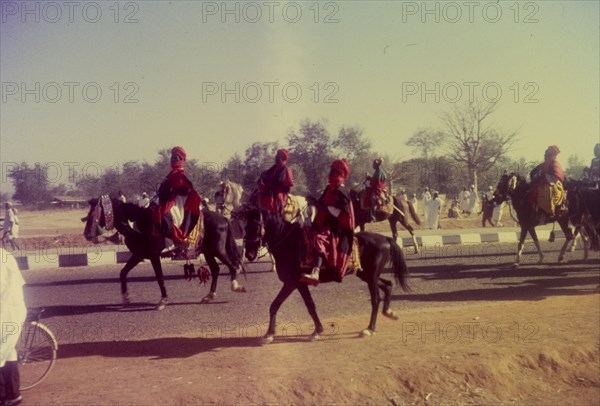 Procession for Ramadan. A group of Nigerian men dressed in ceremonial attire ride horseback in a procession celebrating the end of Ramadan. Zaria, Nigeria, 1958. Zaria, Kaduna, Nigeria, Western Africa, Africa.