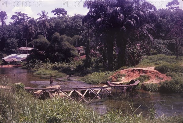 Collapsed bridge near Ore. The twisted girders of a collapsed bridge near Ore lie semi-submerged in a river. The bridge was demolished in raids carried out during the Nigerian Civil War (1967-70). Near Ore, Lagos, Nigeria, circa 1970., Lagos, Nigeria, Western Africa, Africa.