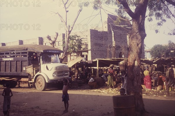 Market outside a damaged church. Street traders set up their stalls outside the remains of church that has been damaged during the Nigerian Civil War (1967-70). Onitsha, Nigeria, circa 1970. Onitsha, Anambra, Nigeria, Western Africa, Africa.