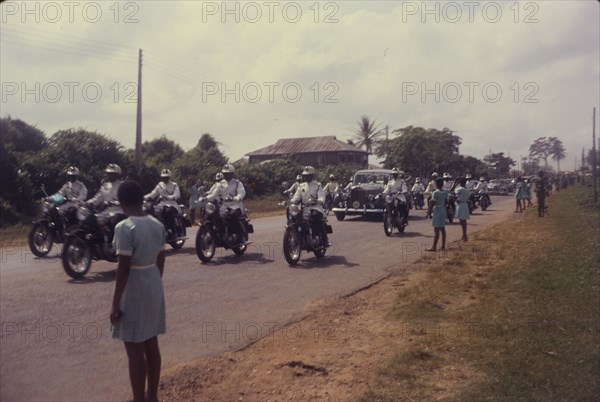 General Gowon approaches. Schoolgirls watch from a roadside as General Gowon, Head of the Federal Military Government of Nigeria, approaches in a car accompanied by a police escort. Nigeria, circa January 1970. Nigeria, Western Africa, Africa.