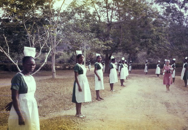 Welcome for an Archbishop. Uniformed nurses line the driveway outside a Church of Nigeria hospital, ready to welcome an Archbishop. Nigeria, February 1963. Nigeria, Western Africa, Africa.