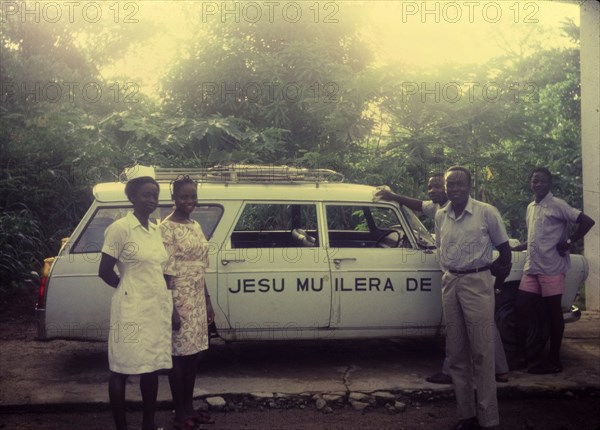 Mobile clinic, Nigeria. Workers at a Church of Nigeria hospital pose for the camera beside an estate car used as a mobile clinic. Nigeria, circa 1972. Nigeria, Western Africa, Africa.