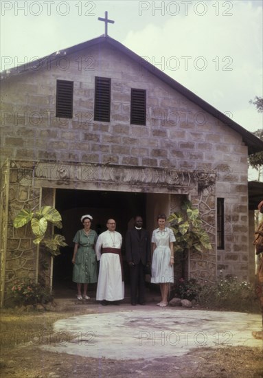 Archbishop visits a hospital chapel. Staff at a Church of Nigeria hospital stand at the doorway of the hospital chapel in the company of a visiting Archbishop. Nigeria, February 1963. Nigeria, Western Africa, Africa.