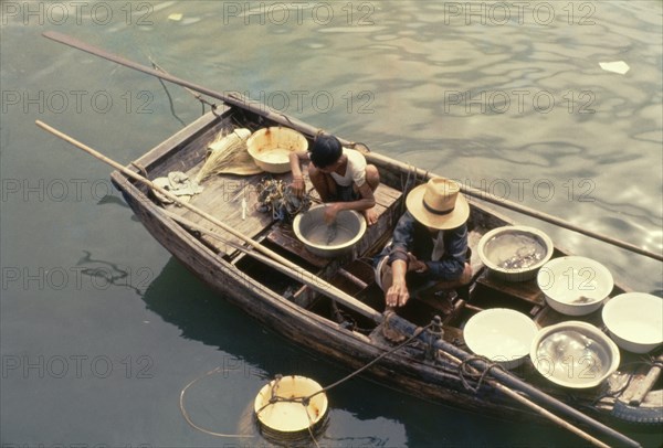 Hong Kong fishermen. Two fishermen aboard an open sampan collect their fresh catch in bowls on the deck. Sham Shui Po, Hong Kong, People's Republic of China, August 1960. Sham Shui Po, Hong Kong, China, People's Republic of, Eastern Asia, Asia.