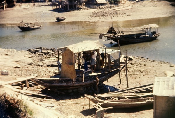 Barber's shop on a Chinese sampan. A small sampan grounded on the shore, serves as an unusual barber's shop. Tai Po, Hong Kong, People's Republic of China, August 1960. Tai Po, Hong Kong, China, People's Republic of, Eastern Asia, Asia.