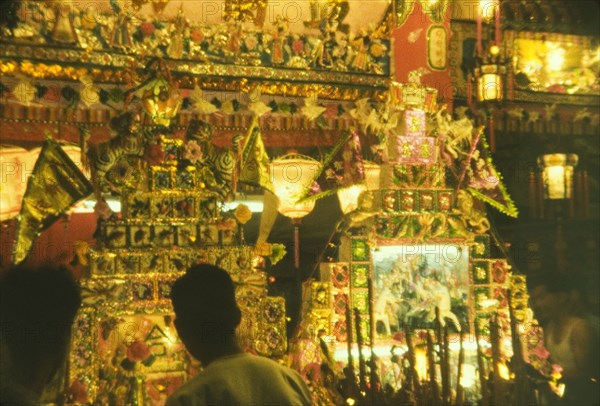 Festival stall, Hong Kong. Chinese lanterns illuminate a ornate festival stall decorated with gilded images, flags and incense. Hong Kong, People's Republic of China, September 1960. Hong Kong, Hong Kong, China, People's Republic of, Eastern Asia, Asia.