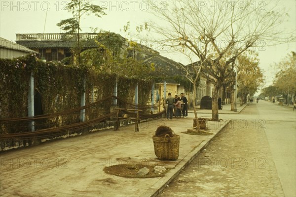 Hanging ropes in Macau. A small group of people unwind lengths of rope from baskets on the roadside, hanging them from fences bordering the pavement. Macau, People's Republic of China, January 1961. Macau, Macau, China, People's Republic of, Eastern Asia, Asia.