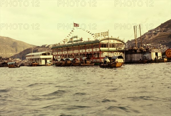 Floating seafood restaurant, Hong Kong. Sampans ferry customers across Aberdeen Bay to sample the delights of the famous Tai Bak floating seafood restaurant moored in the harbour. Aberdeen, Hong Kong, People's Republic of China, January 1961. Aberdeen, Hong Kong, China, People's Republic of, Eastern Asia, Asia.