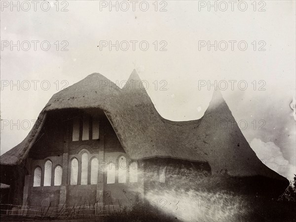 Anglican Cathedral on Namirembe Hill. Exterior view of a cathedral with a thatched roof and mud-plastered walls, identified in the original caption as having been 'built by forced labour'. Kampala, Uganda, 1906. Kampala, Central (Uganda), Uganda, Eastern Africa, Africa.