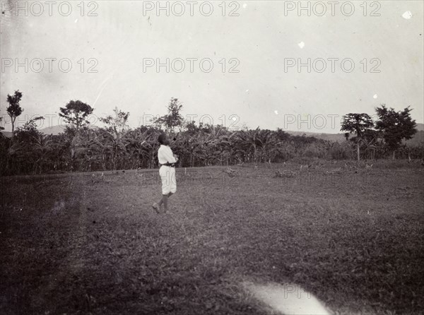 Playing football. An African boy in a field is captioned as 'playing football'. Uganda, 1906. Uganda, Eastern Africa, Africa.