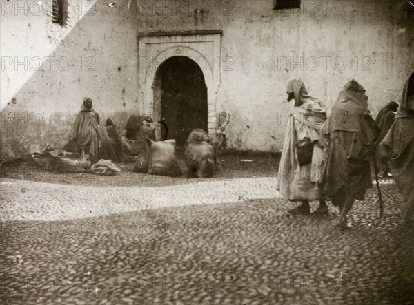 Street traders, Casablanca. Street traders attempt to catch passing trade on a cobbled street in the shadow of the city walls. Casablanca, Morocco, 1898. Casablanca, Casablanca, Morocco, Northern Africa, Africa.