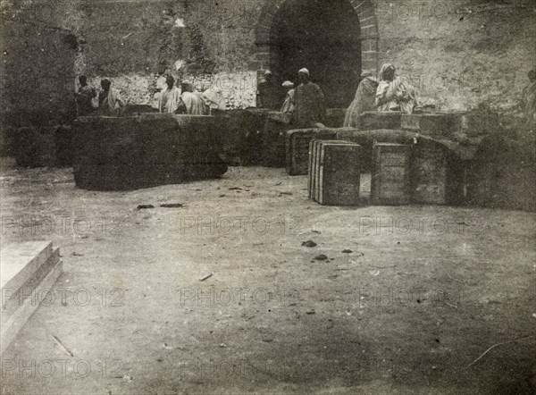 Hunter's store'. Moroccan men congregate around several large crates placed on the ground. Originally captioned as 'Hunter's store', it is unclear whether 'Hunter' is the same 'Hunter' who is travelling with Frederick Stanbury at this time, or a reference to the practice of hunting. Safi, Morroco, 1898. Safi, Safi, Morocco, Northern Africa, Africa.