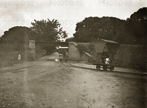 The road from Kilindini to Mombasa. A road junction on the Kilindini-Mombasa road, showing the unusual railway carts that run parallel to the road on a miniature track. A full scale railway track crosses the road over a bridge in the distance. Near Mombasa, British East Africa (Kenya), 1906., Coast, Kenya, Eastern Africa, Africa.