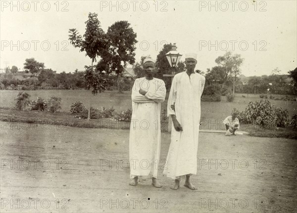 Domestic servants, Kenya. Two African men dressed in long white robes are pictured against the backdrop of an orderly garden. Captioned as 'two boys', they are probably domestic servants. British East Africa (Kenya), 1906. Kenya, Eastern Africa, Africa.