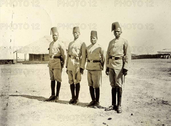 Four askaris of the King's African Rifles. Four uniformed askaris (soldiers) wearing fez hats line up for the camera. British East Africa (Kenya), 1906. Kenya, Eastern Africa, Africa.