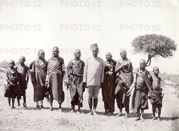 Group of Maasai. The Maasai women shown here wear the traditional dress of married women and may be the wives of the central male figure. He wears a uniform of colonial design and a fez hat. He is possibly a policeman or guard. British East Africa (Kenya), 1906. Kenya, Eastern Africa, Africa.