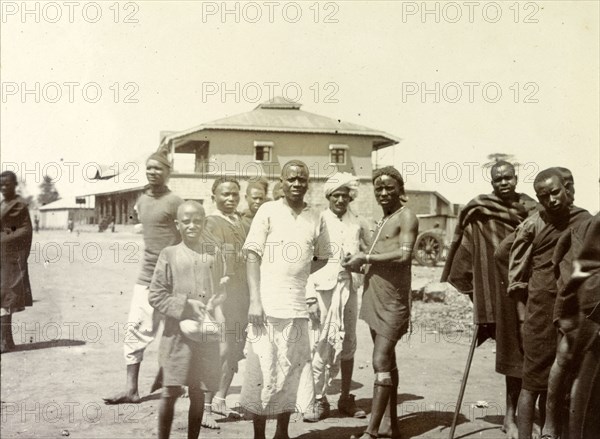 Kenyan men at the station. Local Kenyan men and boys gather for the camera outside a railway station. They may be part of Frederick Stanbury's safari servant entourage who accompanied him on his trip to the Lake Baringo area. Nairobi, British East Africa (Kenya), 1906. Nairobi, Nairobi Area, Kenya, Eastern Africa, Africa.