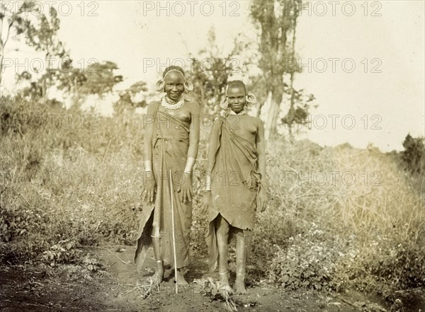 Two Kikuyu women. Two young Kikuyu women wearing traditional dress and masses of hooped earrings, smile at the camera. British East Africa (Kenya), 1906. Kenya, Eastern Africa, Africa.