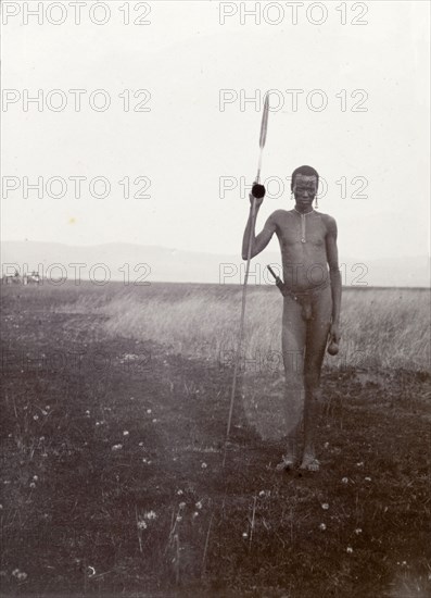 Portrait of a Kenyan man, 1906. Portrait of a naked Kenyan man holding a long spear taken on safari by Frederick Stanbury's hunting party. British East Africa (Kenya), 1906. Kenya, Eastern Africa, Africa.