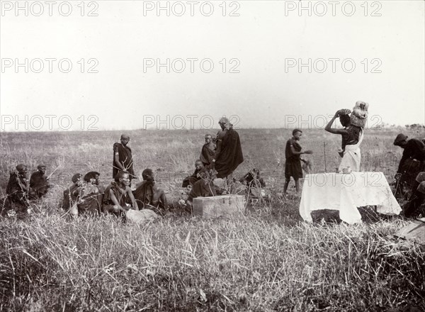 Frederick Stanbury's porters. Frederick Stanbury's porters unload luggage to set up camp on a safari trip in the wilds near Lake Baringo. Stanbury makes a note in the original caption to 'Notice (the) Cloth' on the table, a hint of luxury in the wilderness. British East Africa (Kenya), 1906. Kenya, Eastern Africa, Africa.
