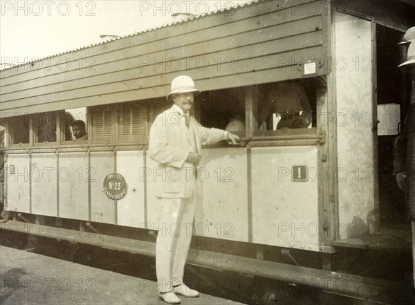 Colonel Will' at Kisumu. A European man identifed as 'Colonel Will' rests his hand on a bar running along the side of a train. Kisumu, British East Africa (Kenya), 1906. Kisumu, Nyanza, Kenya, Eastern Africa, Africa.