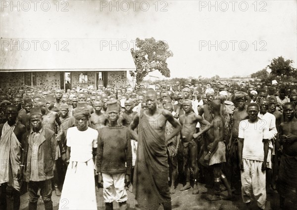 African workers on strike, Kisumu. A large crowd of African men and women stands outside a European-style masonry building. A caption calls this the 'first strike in East Africa' and says that it was organized by Indians. Kisumu, British East Africa (Kenya), 1906. Kisumu, Nyanza, Kenya, Eastern Africa, Africa.
