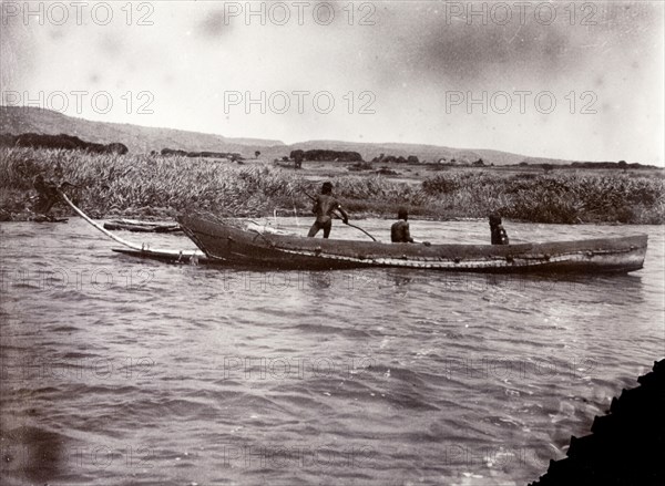Canoe made with no nails. Three African men pilot a large wooden canoe on Lake Victoria. According to the original caption, there are 'No Nails Used' in the construction of this vessel. Lake Victoria, British East Africa (Kenya), 1906., Nyanza, Kenya, Eastern Africa, Africa.