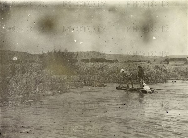 Coming ashore at Lake Victoria. A tiny wooden vessel is brought ashore by three African men on the banks of Lake Victoria. Lake Victoria, British East Africa (Kenya), 1906., Nyanza, Kenya, Eastern Africa, Africa.