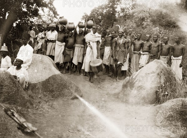 Safari porters gather for a feast. African porters await a feast before setting off on a 30-day march to the Congo. German East Africa (Tanzania), 1906. Tanzania, Eastern Africa, Africa.