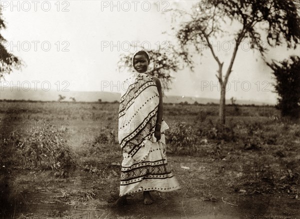 Kavirondo girl. Portrait of a young Kenyan girl dressed in a patterned wraparound robe that covers her head and body. Kavirondo, British East Africa (Kenya), 1906. Kavirondo, Nyanza, Kenya, Eastern Africa, Africa.