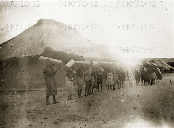 Porters in German East Africa. A line of African porters carry crates of goods to the Congo on their shoulders. German East Africa (Tanzania), 1906. Tanzania, Eastern Africa, Africa.